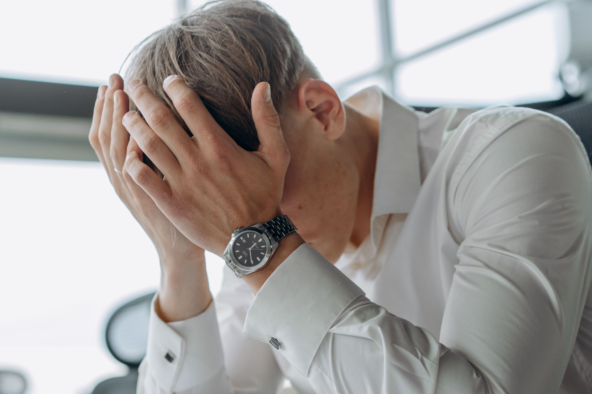 A business professional showing stress and fatigue with head in hands.